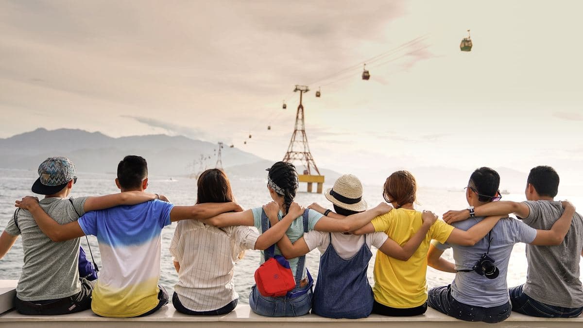 A group of friends sitting together with their arms around each other, looking out at the view